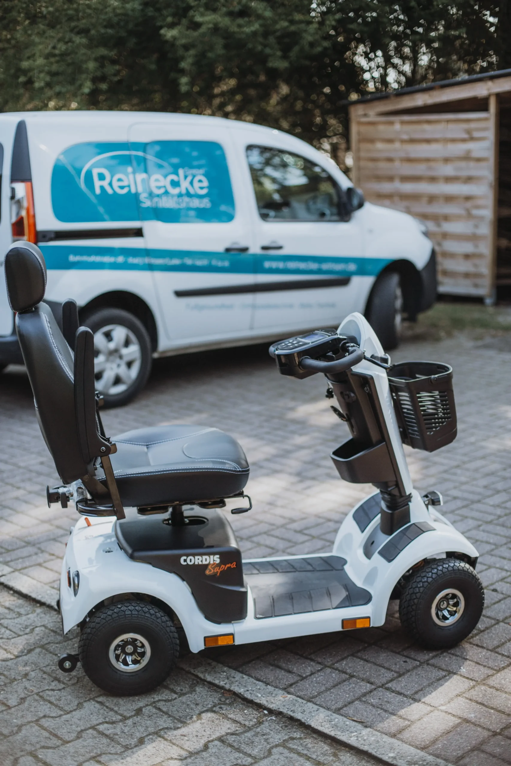 Weißes Elektromobil mit schwarzem Sitz und Korb vorne, Modell 
